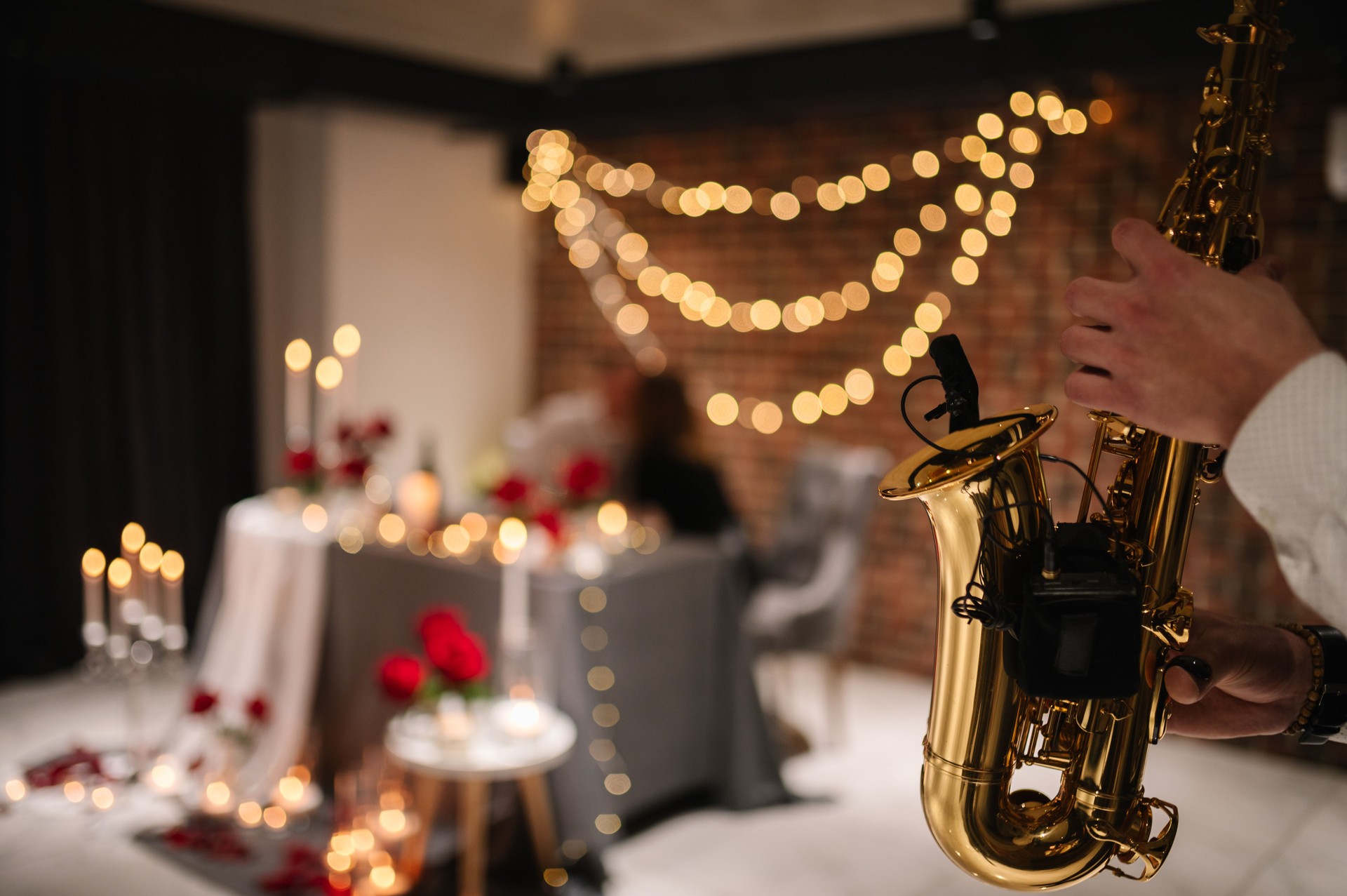 Saxophonist's hands while playing jazz. Musician hold sax at romantic date on Valentine's Day in restaurant. Man performing on saxophone at party or wedding. Jazz music concept closeup. Space for text